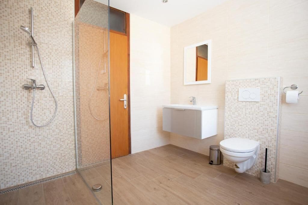 Une salle de bain moderne avec une douche à parois de verre, un lavabo blanc et des toilettes.
