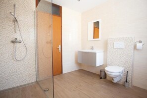 A modern bathroom with a glass shower enclosure, a white sink, and a toilet. - Hostel LakeBled (Bled)
