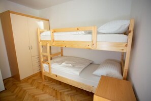 Dormitorio con literas, un armario de madera y una pequeña mesa.