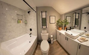 Une salle de bain moderne équipée d’une baignoire, de toilettes et de deux lavabos.