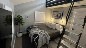 Une chambre à coucher de taille réduite, avec un lit superposé, un bureau et une plante en pot.