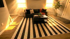 Un salon avec un tapis à rayures, un canapé, une table basse et une plante en pot.