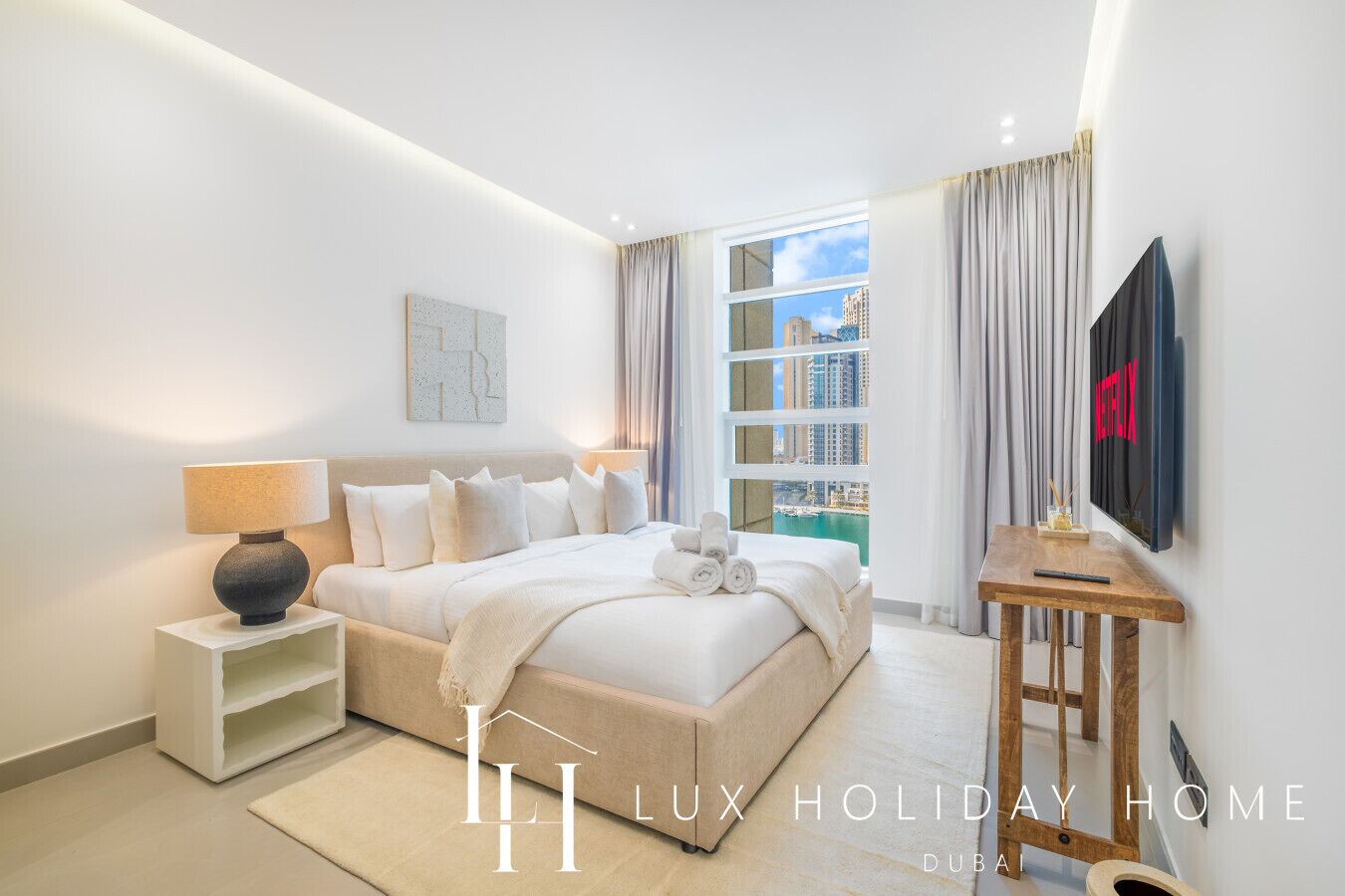 Une chambre d’hôtel moderne avec un grand lit, des tables de chevet, une télévision et une vue sur la ville.