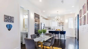 A modern kitchen with white cabinets, a dining area with a glass table, and a yellow rug. - Rooftop Views Patio Lounge Near Downtown Nashville (Nashville)