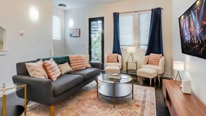 A modern living room with a grey sofa, two armchairs, a glass coffee table, and a patterned rug. - Rooftop Views Patio Lounge Near Downtown Nashville (Nashville)