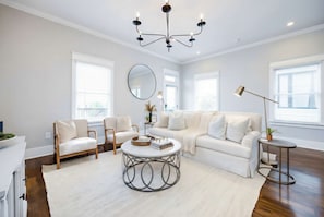 A modern living room with a white sofa, two armchairs, a round coffee table, and a chandelier. - Private Pool Game Room Compound Minutes to Broadway (Nashville)