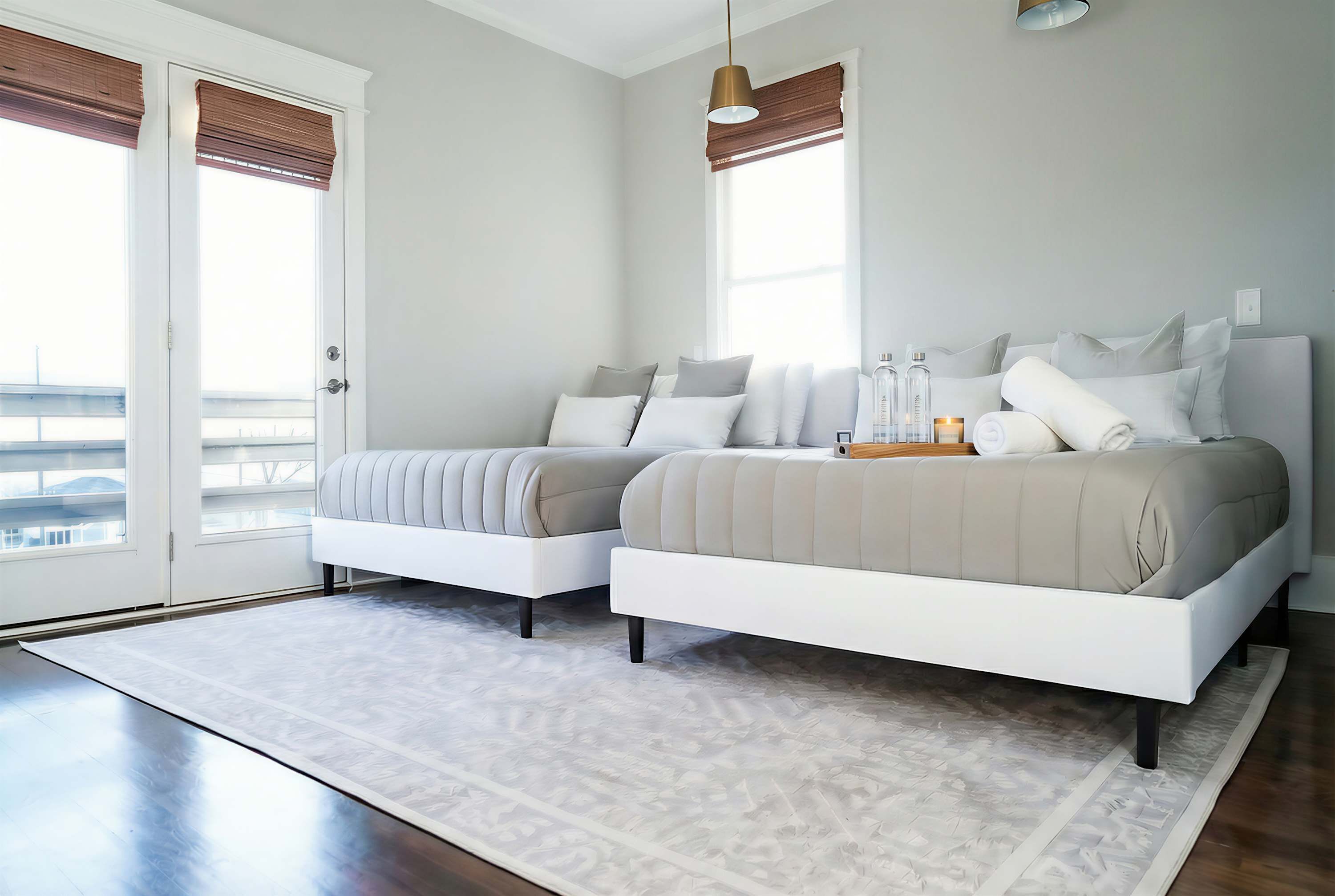 A modern bedroom with two beds, a large window, and a view of the outdoors.