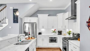 Una cocina moderna con armarios blancos, electrodomésticos de acero inoxidable y piso de madera.