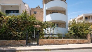 A multi-story residential building with a stone facade, a balcony, and a gated entrance. - Sun Studio - Sitia Cozy Stay With Mountain Views (Sitia)