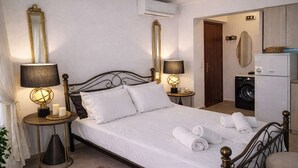 A neatly made bed with white linens, two bedside lamps, and a large mirror on the wall. - Sun Studio - Sitia Cozy Stay With Mountain Views (Sitia)
