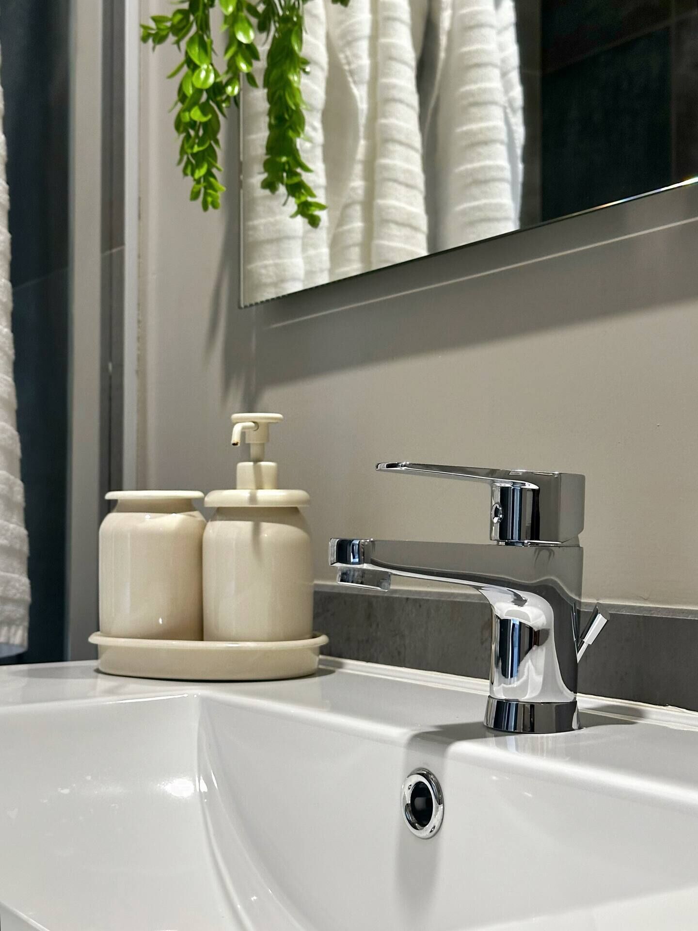 A bathroom sink with a chrome faucet and two soap dispensers on a white countertop.