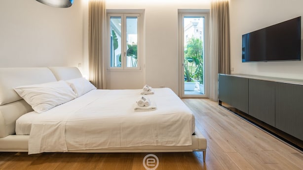 A modern bedroom with a bed, a TV, and a balcony view. - Loft 4 Via Campidano – Your city-centre retreat (Cagliari)