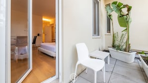 A modern interior with a glass door leading to a room, a white chair, a small table, and a potted plant. - Loft 4 Via Campidano – Your city-centre retreat (Cagliari)