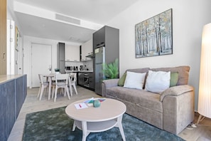 Ein zeitgemäßer Wohnbereich mit Sofa, rundem Couchtisch, Essplatz und Küche.