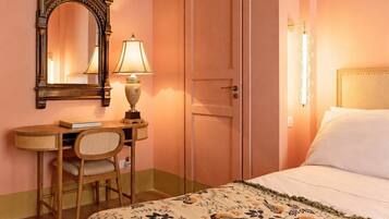 A bedroom with a bed, a desk with a chair, a door, and a mirror.