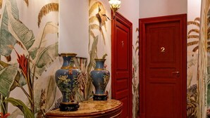 A hallway with a checkered floor, a red door, and wall-mounted light fixtures. - Le Stanze di Monserrato (Catania)