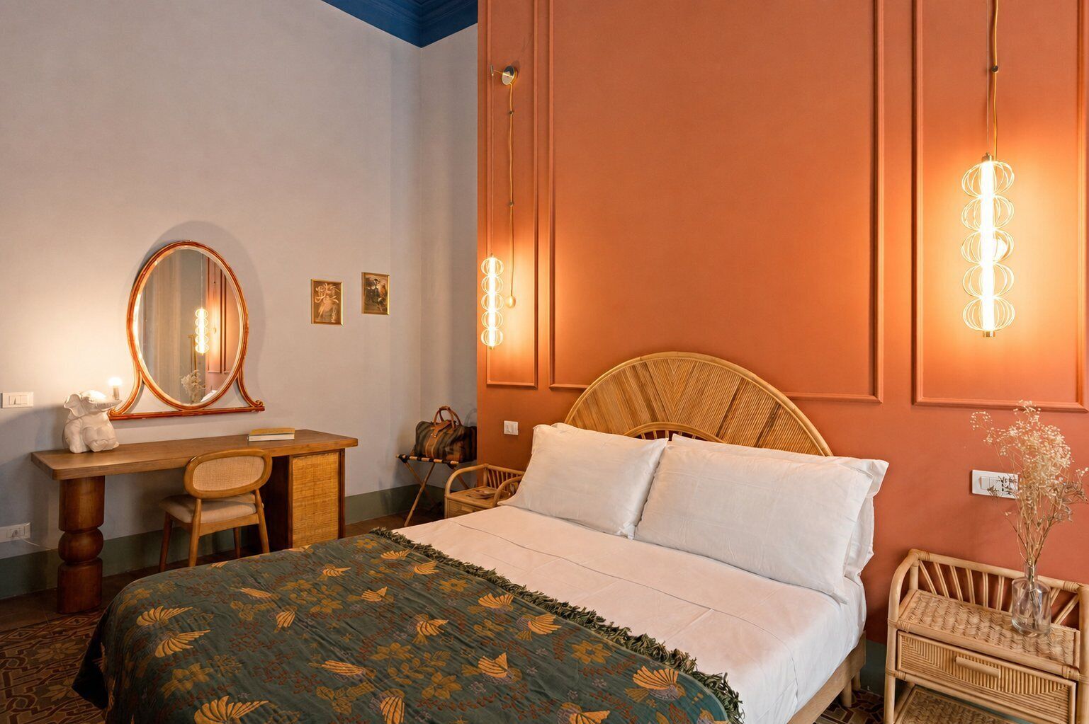 Habitación de hotel con cama, escritorio, silla, espejo e iluminación en la pared.