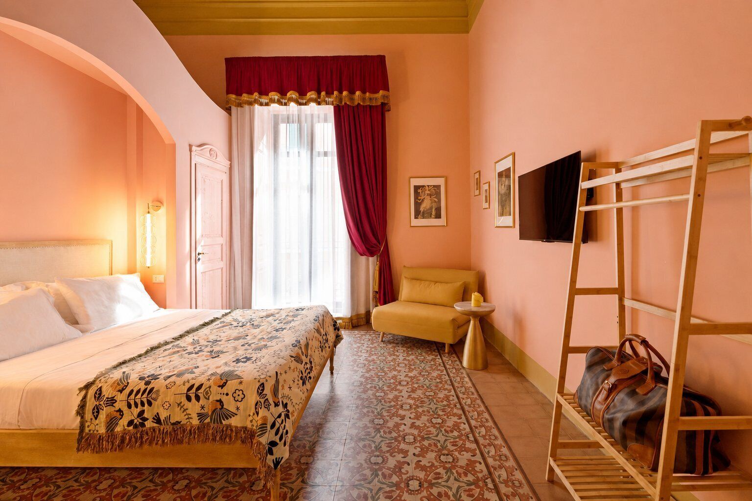 A hotel room with a bed, a chair, a TV, and a luggage rack.