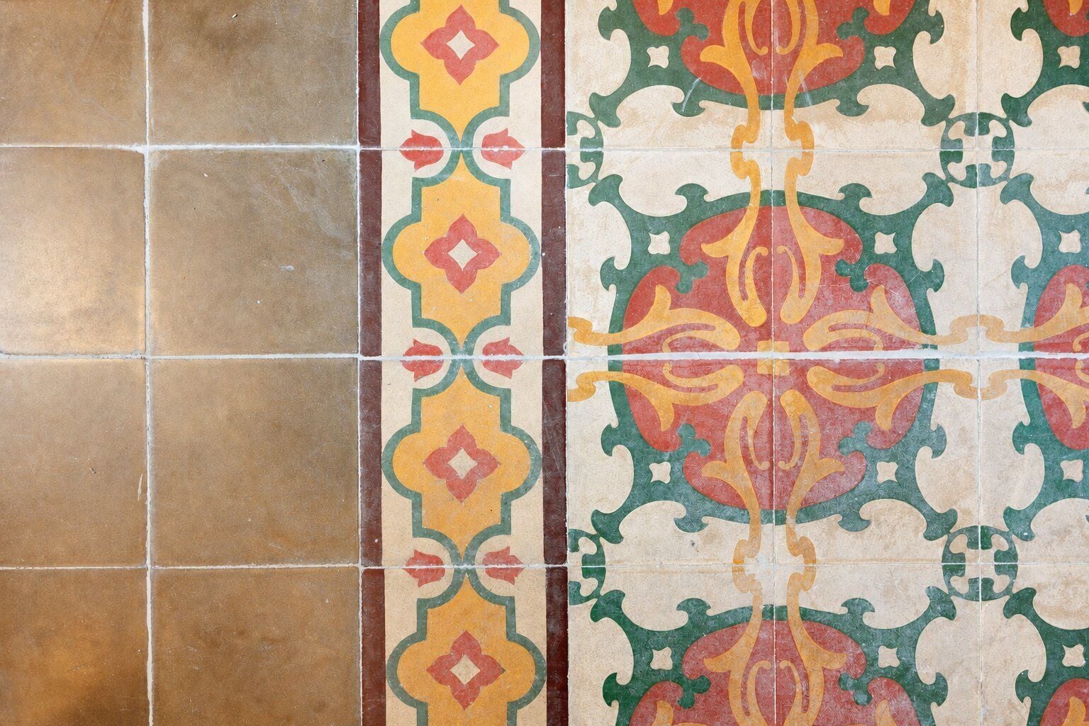 A section of a tiled wall with a decorative border and plain tiles.
