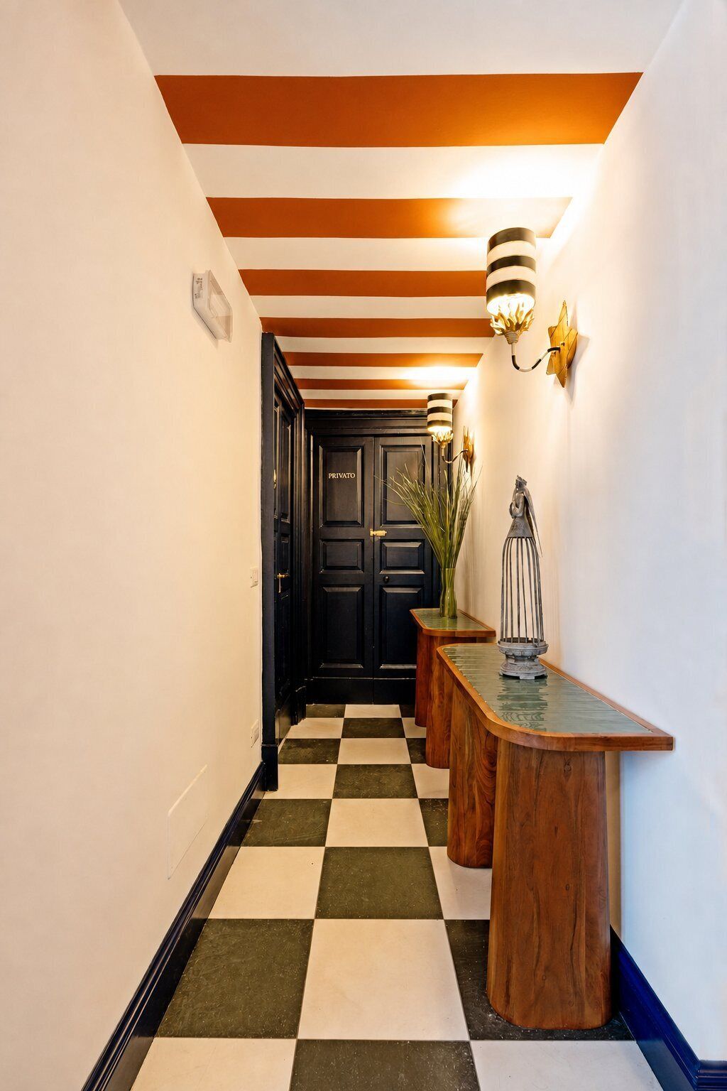 A hallway with a checkered floor, a wooden bench, a black door labeled 'PRIVATE,' and a wall-mounted light fixture.