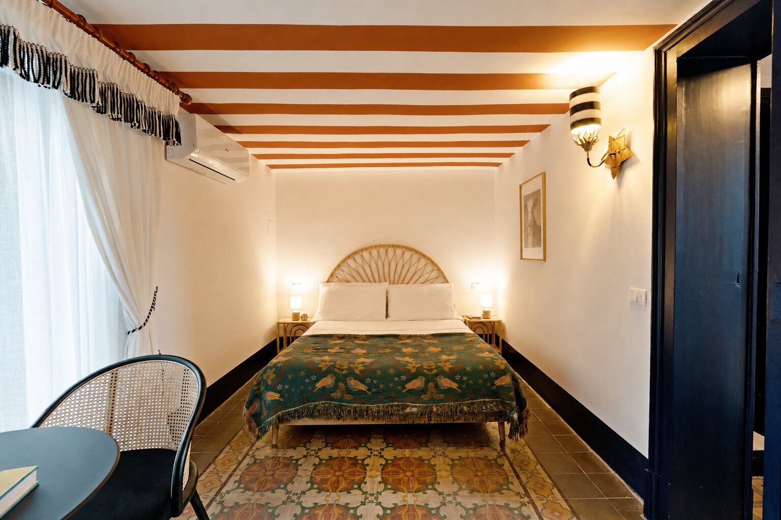 Une chambre d’hôtel avec un lit, deux lampes de chevet, une chaise, un tapis à motifs et une porte.