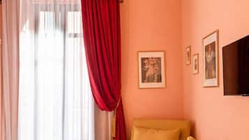 A room with a bed, a chair, a small table, and a wall-mounted TV.