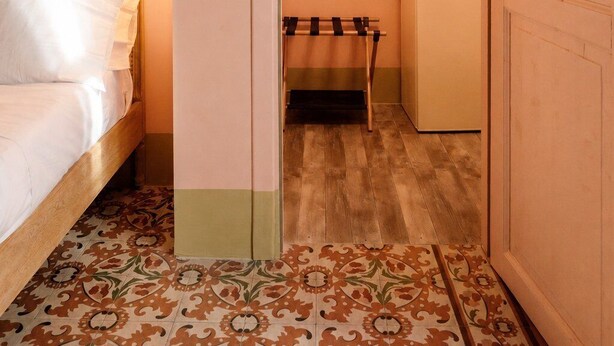 A hotel room with a bed, a small table with a kettle, and a door leading to another room. - Le Stanze di Monserrato (Catania)
