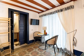 A room with a dark door, a small table with a lamp, two chairs, and a patterned floor. - Le Stanze di Monserrato (Catania)