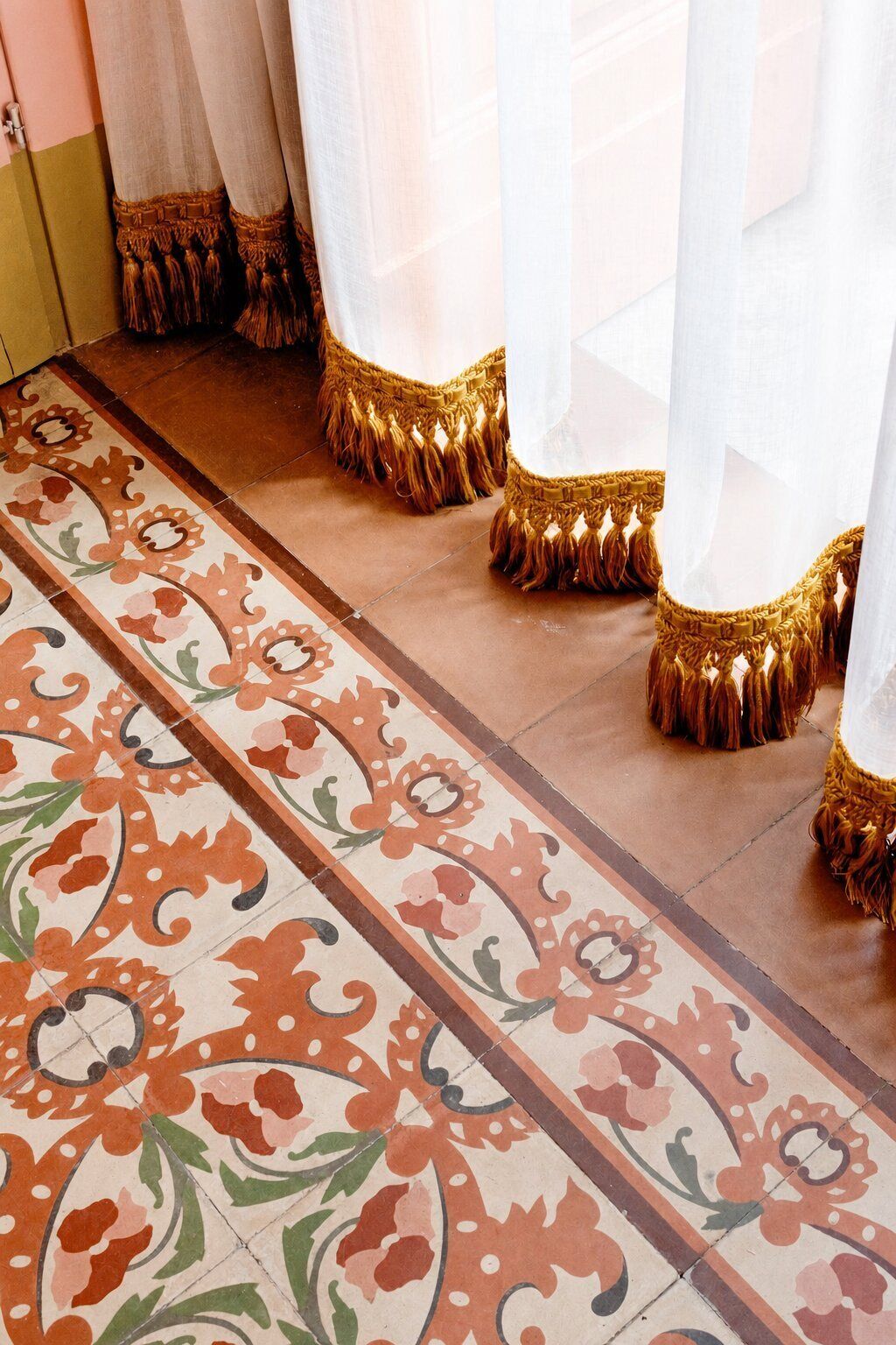 A patterned floor with a decorative border and a series of curtains with tassels.