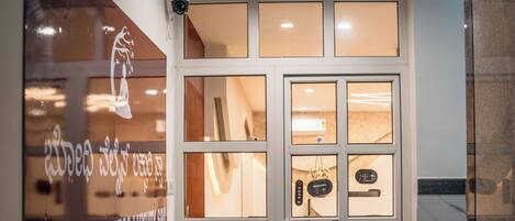 Una entrada moderna con puerta de vidrio, mostrador de recepción y cartel para Bodhi Wellness Luxury Spa.