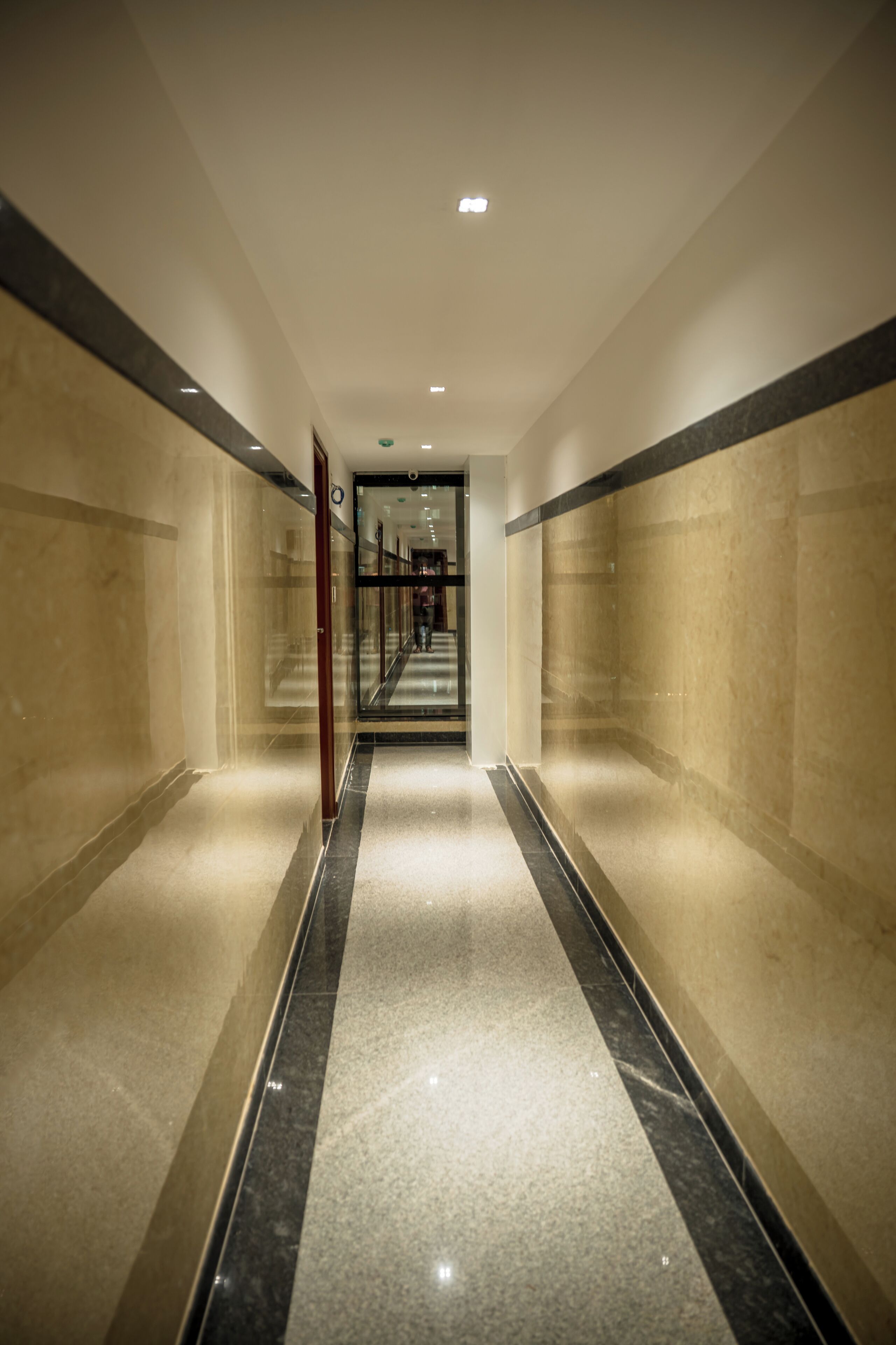 A corridor with marble flooring and walls, leading to a staircase.