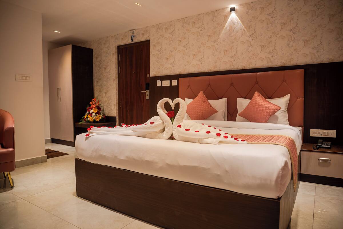 Una habitación de hotel con una cama grande, un cabecero de madera y una mesita de noche con una lámpara.