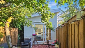 A patio with a brick floor, a wooden fence, and a table with chairs. - Entire Malmö guest house with private terrace, king bed & free parking (Malmö)