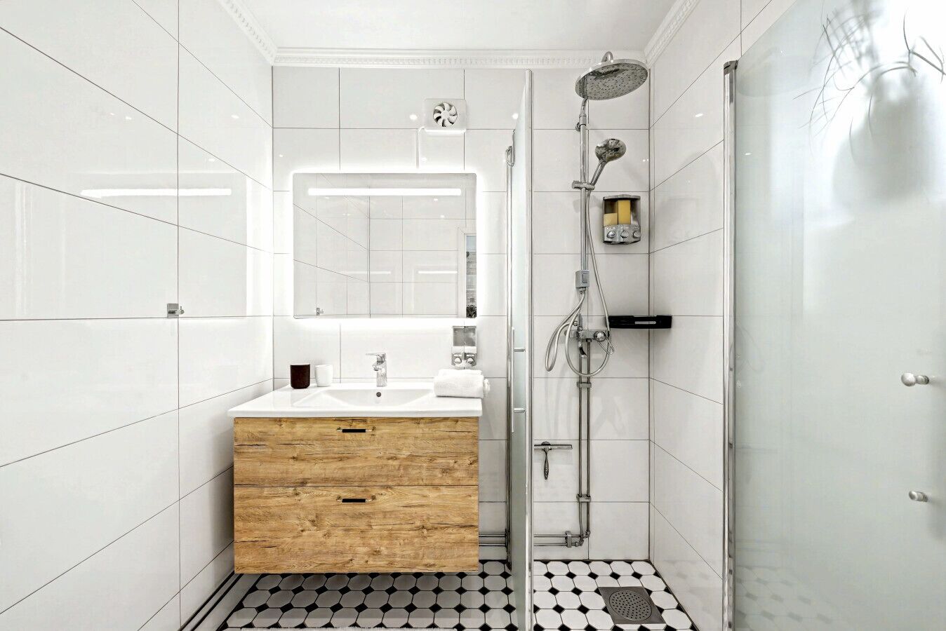 Un baño moderno con tocador de madera, un espejo grande y ducha con cabezal de mano.