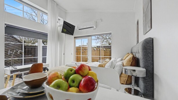 A modern, well-lit bedroom with a bed, a TV mounted on the wall, and a bowl of fruit on the bedside table. - Entire Malmö guest house with private terrace, king bed & free parking (Malmö)