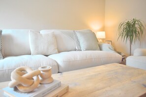 A cozy living room with a light-colored sofa, a wooden coffee table, and a potted plant. - Luxurious Amberley House I Near Goodwood Events I With Garden & Parking (Tangmere)