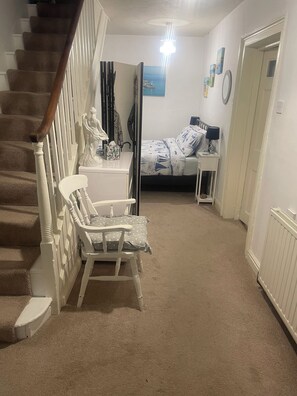 A bedroom with a bed, a chair, a nightstand, a dresser, a mirror, and a staircase. - Spacious self contained historical apartment in a central and level location (Falmouth)