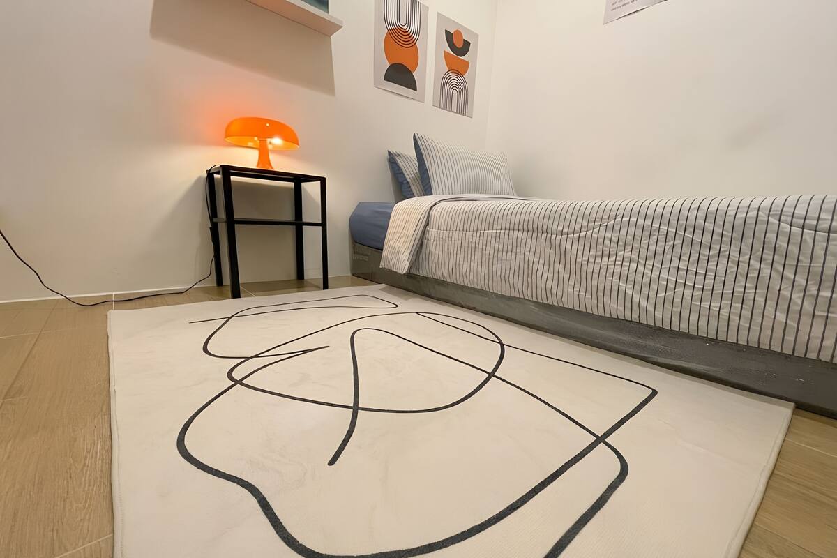 Un dormitorio con cama, mesita de noche con lámpara y arte abstracto en la pared.