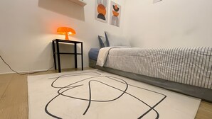 A bedroom with a bed, a bedside table with a lamp, and abstract wall art.