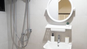 A bathroom with a shower, sink, and mirror.