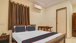 A hotel room with a bed, a bedside table with a phone, a small table, a chair, and an air conditioning unit. - Hotel O by OYO New Hotel Hamsa (Hyderabad)