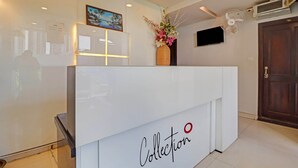A reception desk with a 'Collection' sign, a framed picture, a vase with flowers, and a mounted TV. - Hotel O by OYO New Hotel Hamsa (Hyderabad)