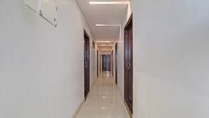 A long, narrow hallway with white walls and a shiny tiled floor. - Hotel O by OYO New Hotel Hamsa (Hyderabad)