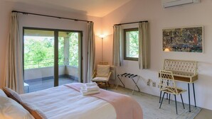 Een slaapkamer met een bed, een stoel, een bureau en een schilderij aan de muur.