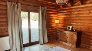 Una habitación tipo cabaña de madera con una cama, un armario, una lámpara y vistas por una ventana.