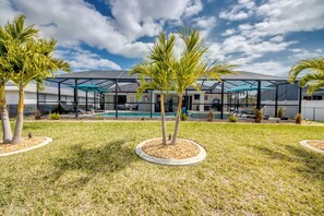 A modern building with a pool, surrounded by well-maintained grass and palm trees. - Intervillas Florida - Villa Emerald (Cape Coral)