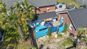 Vue aérienne d’un quartier résidentiel avec une piscine, du mobilier de jardin et des palmiers.