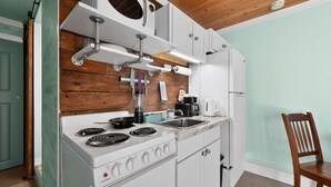 Een kleine keuken met witte apparaten, houten wandbekleding en een houten plafond.