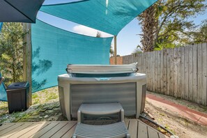 Un bain à remous avec une terrasse en bois et une clôture en bois en arrière-plan.