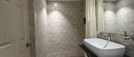 A bathroom with a bathtub, a shower, tiled walls, and a door.